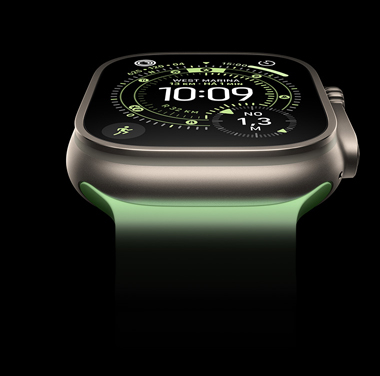 Close de um Apple Watch Ultra 3 com caixa natural de titânio sobre um fundo preto. A tela mostra a hora e outros dados dinâmicos.