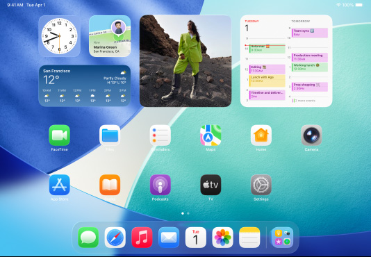 三款型號的 iPad 橫向放置，放在中間的一部位於另外兩部 iPad 的前方。Apple Pencil 以磁力貼合在中間那部 iPad 的頂部，其主畫面展示 Liquid Glass 效果的彩色 app 圖像。位於左邊的 iPad 螢幕正展示預覽程式 app，而右邊的螢幕則展示主畫面，多個檔案從 Dock 上以扇形垂直展開