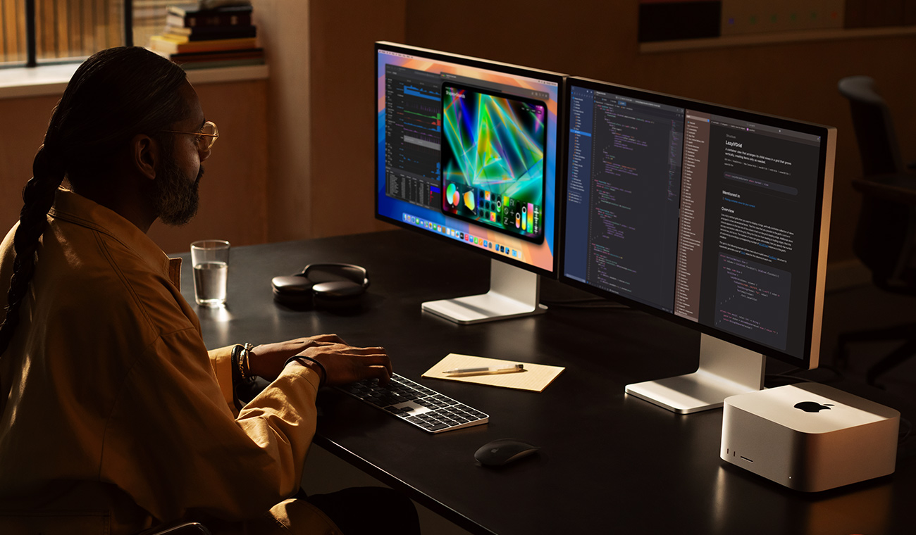 Profesionist lucrând cu Mac Studio și două monitoare Studio Display
