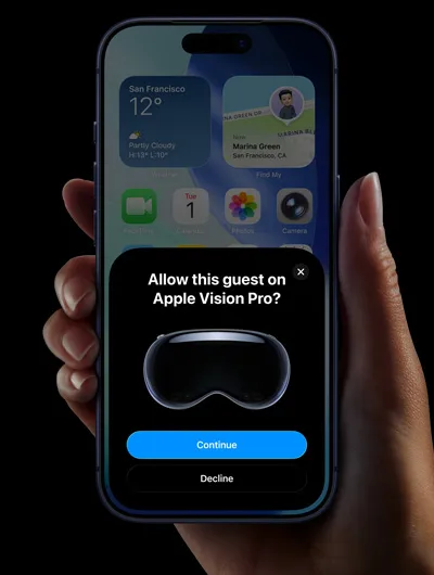 一隻手拿著 iPhone，iPhone 螢幕上顯示包含訊息的視窗，詢問使用者要在 Apple Vision Pro 上允許此訪客嗎，並提供繼續與拒絕按鈕