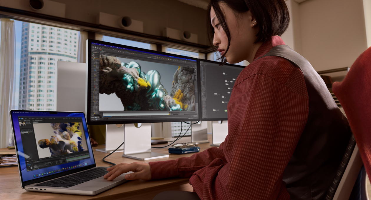 Une personne dans un bureau travaille sur un MacBook connecté à un Studio Display XDR via un port Thunderbolt 5
